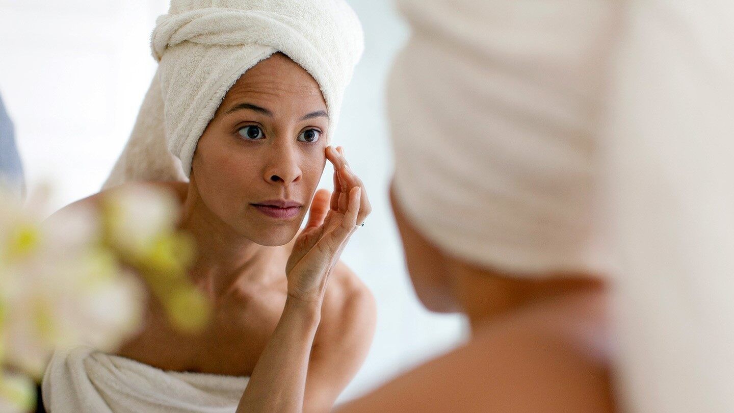 a woman checking her skin in a mirror