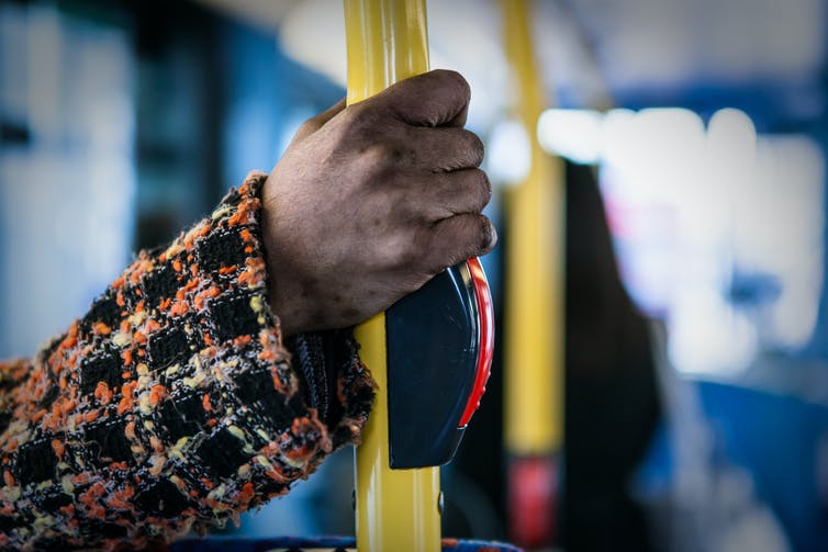 A hand holding a railing on a bus or train.