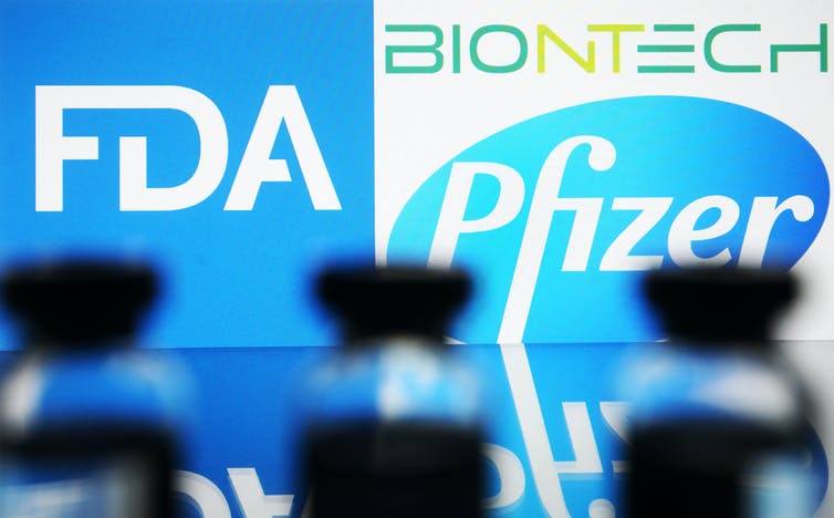 Vaccine vials lined up in front of the FDA and Pfizer BioNTech logos