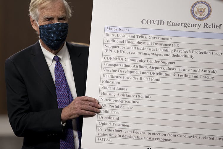 Maine Independent Sen. Angus King sets up a sign describing a bipartisan proposal for a Covid-19 relief bill on Capitol Hill.