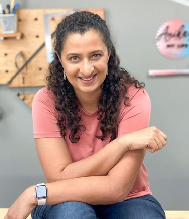 Smiling woman sits with her arms crossed in her lap