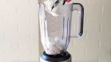 Ice cream being placed in blender jar.