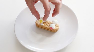 Attaching marshmallow wheels to cookie with icing