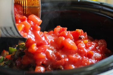 Diced tomatoes being poured into a crock pot