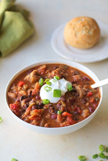 Bowl of chili with sour cream and green onion