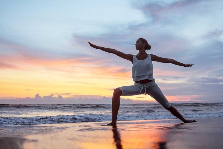 Young woman doing yoga at sunset