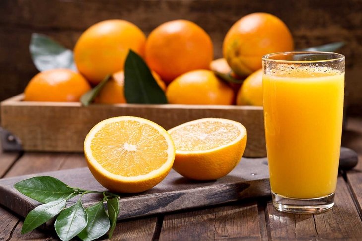 glass of fresh orange juice with fresh fruits on wooden table