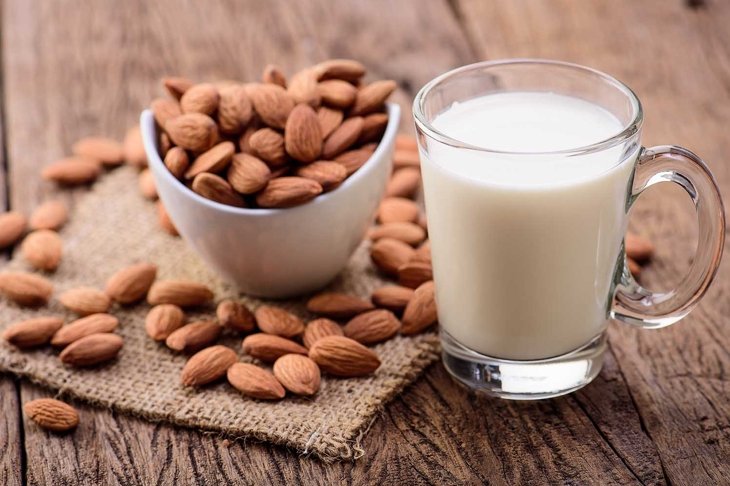 Almond milk in glass with almonds