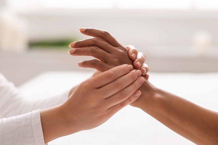 Hand massage. Female therapist pressing specific spots on black lady palm. Professional health and wellness acupressure manipulations, closeup